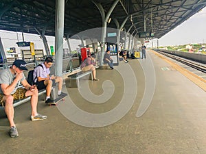 Passengers are waiting the arrival of the airport rail link sky train. People wait in an orderly line behind the yellow arrows poi