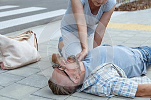 Passerby checks the vital functions of the person who fainted on the street