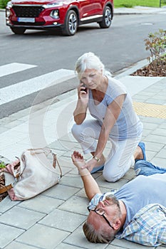 Passerby kneels beside the person who fainted on the street and calls an ambulance