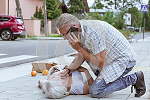 Passerby kneels beside the person who fainted on the street and calls an ambulance