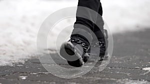 passerby is walking on street at winter day, closeup of feet shod warm shoes outdoor