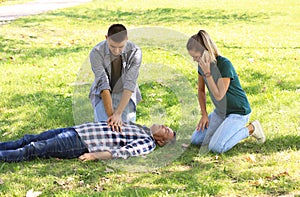 Passersby helping unconscious man outdoors. First aid photo