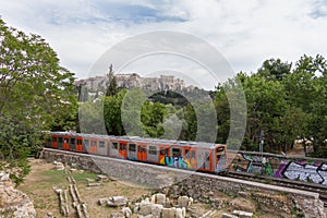 Passing train through Athens Ancient Agora with Acropolis in the