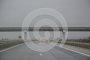 Passing under a bridge on an highway, rainy days, car driving through water from the storm, bad weather