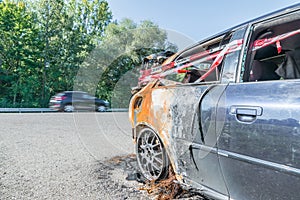 Passing vehicles behind an accident car with police barrier tape with German word for police barricade, Germany