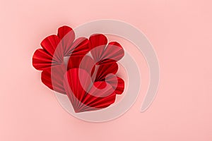Passion bright red paper ribbed heart shape of hearts on soft light pink background, top view, copy space. Valentine day.