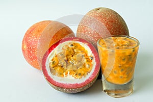 Passion fruit on a white background with whole fruit, halves and passion fruit juice in a glass.