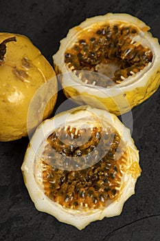 Passion fruit, whole and sliced, on black stone table