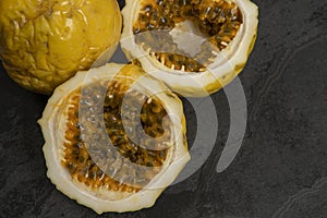 Passion fruit, whole and sliced, on black stone table