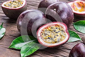 Passion fruits and its cross section with pulpy juice filled with seeds. Wooden background