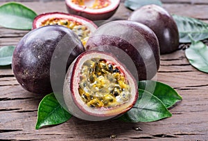 Passion fruits and its cross section with pulpy juice filled with seeds. Wooden background photo