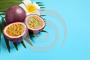 Passion fruits maracuyas, flower and palm leaf on light blue background. Space for text