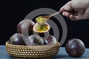 passion fruits within a wooden basket and a wooden spoon over them