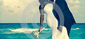 Passionate Afro-American couple kissing on wedding day by the sea