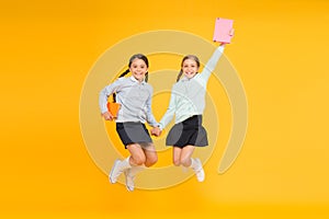 Passionate about books. Happy little girls jumping with books on yellow background. Cute small children smiling with