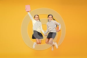 Passionate about books. Happy little girls jumping with books on yellow background. Cute small children smiling with