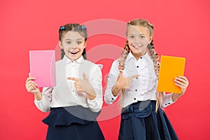 Passionate about books. Happy little girls pointing at books on red background. Cute small children smiling with