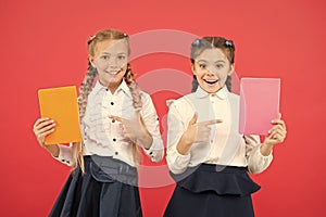 Passionate about books. Happy little girls pointing at books on red background. Cute small children smiling with