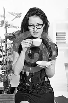 Passionate about coffee. Pretty woman drinking coffee in office. Sexy business woman with teacup sitting on desktop