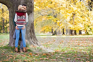 Passionate couple against tree trunk in park during autumn