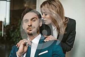 Passionate couple flirts at work. Office romance concept. Caucasian man and woman in love wearing formalwear. Man looks