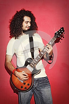 Passionate guitarist happy with beautiful long curly hair playing guitarist