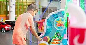 Passionate happy kid boy playing fun games on slot machine in amusement park