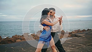 Passionate latino dancers enjoy hot performance on cloudy pier. Couple dancing
