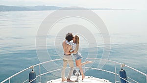 Passionate lovers dancing on bow of deck while sailing on yacht.