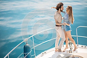 Passionate lovers dancing on bow of deck while sailing on yacht.