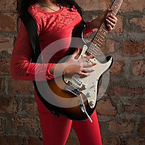 Passionate Music: Young Woman Playing Guitar in front of Retro Brick Wall - Studio Close-Up
