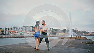 Passionate pair performing latin american dance on embanking. Couple dancing