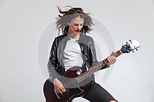 Passionate woman guitarist with flying hair playing