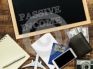 Passive income, financial concept. text PASSIVE INCOME on chalkboard at the wooden table with book bank , money wallet , banknote