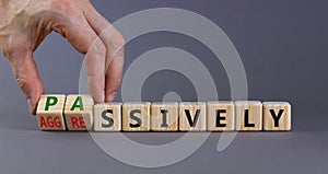 Passively or aggressively symbol. Businessman turns cubes and changes the word passively to aggressively. Psychological and photo