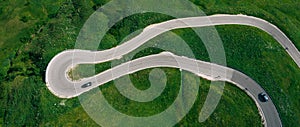 Passo Gardena Green hills Aerial drone shot of curved mountainous road with cars passing through curves. Transportation, safety