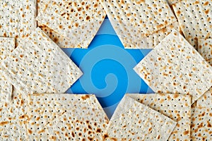 Passover celebration concept. Blue Star of David made from matzah, white and yellow roses, kippah and walnut on bluebackground.