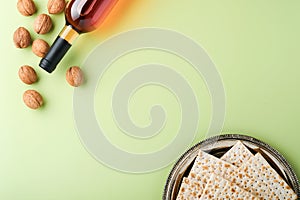 Passover celebration concept. Matzah, red kosher wine and walnut. Traditional ritual Jewish bread on light green background.