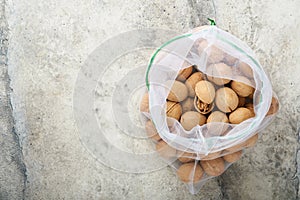 Passover celebration concept. Organic walnuts in eco bags on old grey cracked tile countertop table background. Passover food.