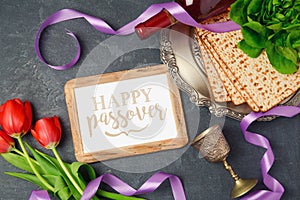 Passover holiday concept matzoh, photo frame and tulip flowers on dark background.