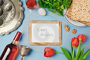 Passover holiday concept with photo frame, seder plate and matzoh on wooden background.