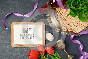 Passover holiday concept seder plate, matzoh and photo frame on dark background.
