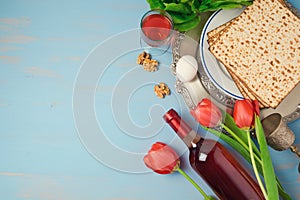 Passover holiday concept seder plate, matzoh and tulip flowers on wooden background.