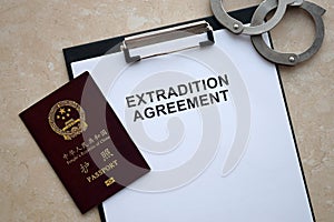 Passport of China Republic and Extradition Agreement with handcuffs on table