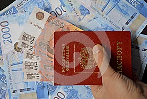 passport of a citizen of Russia in a man's hand and randomly laid out rubles