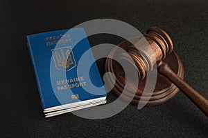 Passport of a citizen of Ukraine and a judicial hammer on a black background. Legal immigration. Obtain citizenship photo
