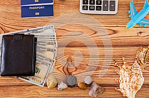 Passport, dollars, calculator, toy airplane on a wooden background. Travel concept.