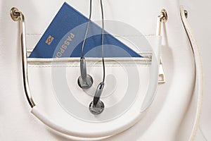 Passport and headphones in famale handbag