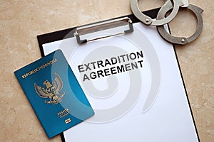 Passport of Indonesia and Extradition Agreement with handcuffs on table