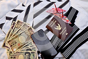 Passport,mobile phone,banknotes, credit card and origami paper birds place on japanese pajamas call as yukata